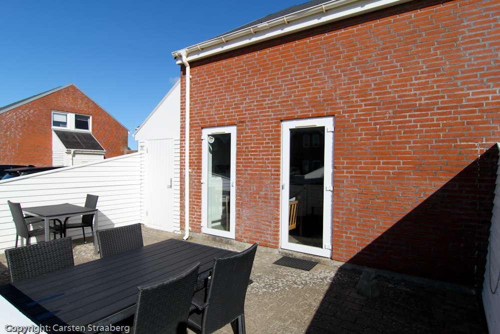 Terrasse med stole og borde. Parasollen står i skuret.